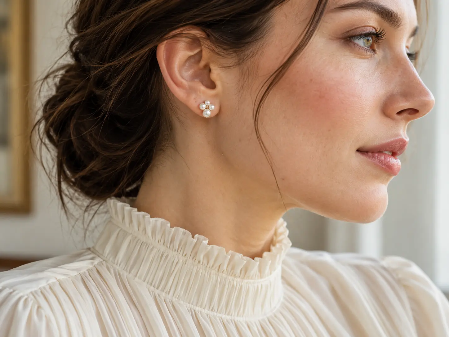 Close side view of a pearl cluster stud with an ivory gathered high-neck blouse