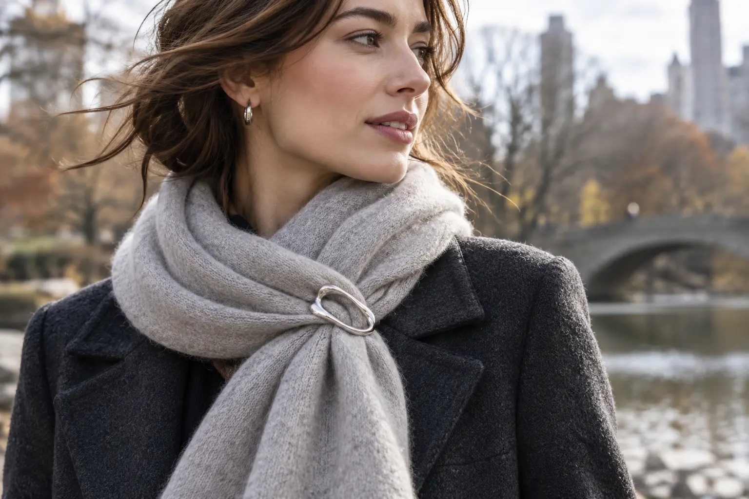 Silver brooch securing a soft wool scarf above the lapel of a winter coat
