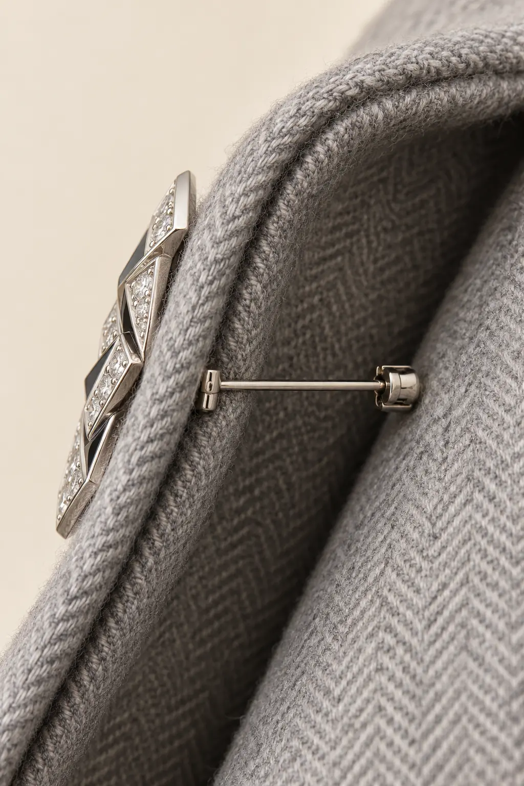 Close view of a silver brooch pin secured through a doubled grey herringbone coat lapel